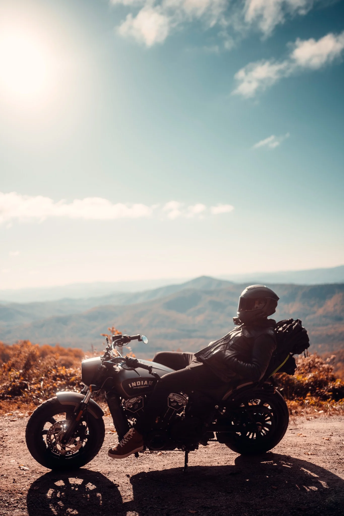 Motorcyclist resting on an Indian Scout with mountain views