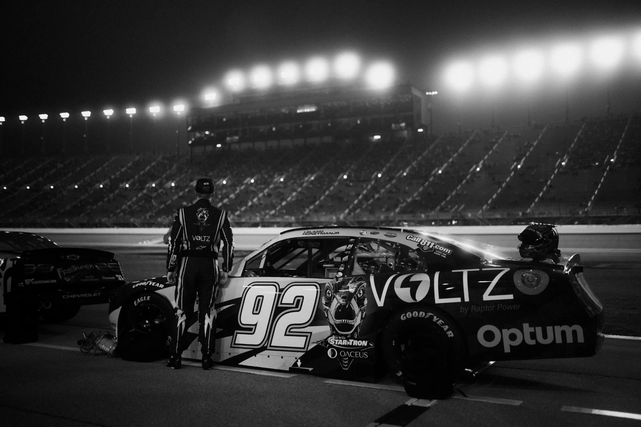 NASCAR driver standing beside the number 92 stock car under speedway lights